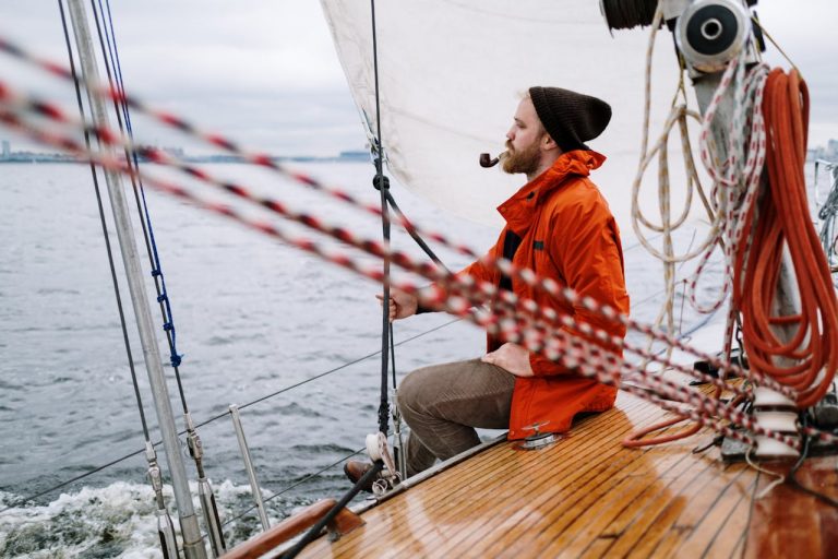 man-in-orange-jacket-sitting-on-brown-wooden-boat