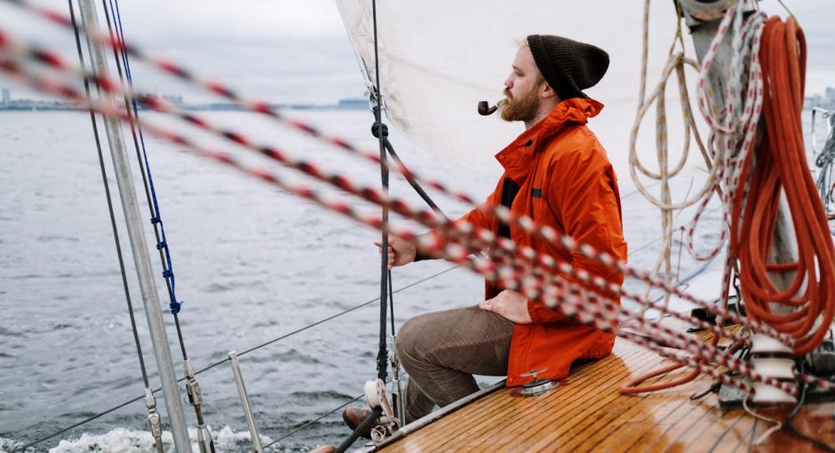 man-in-orange-jacket-sitting-on-brown-wooden-boat